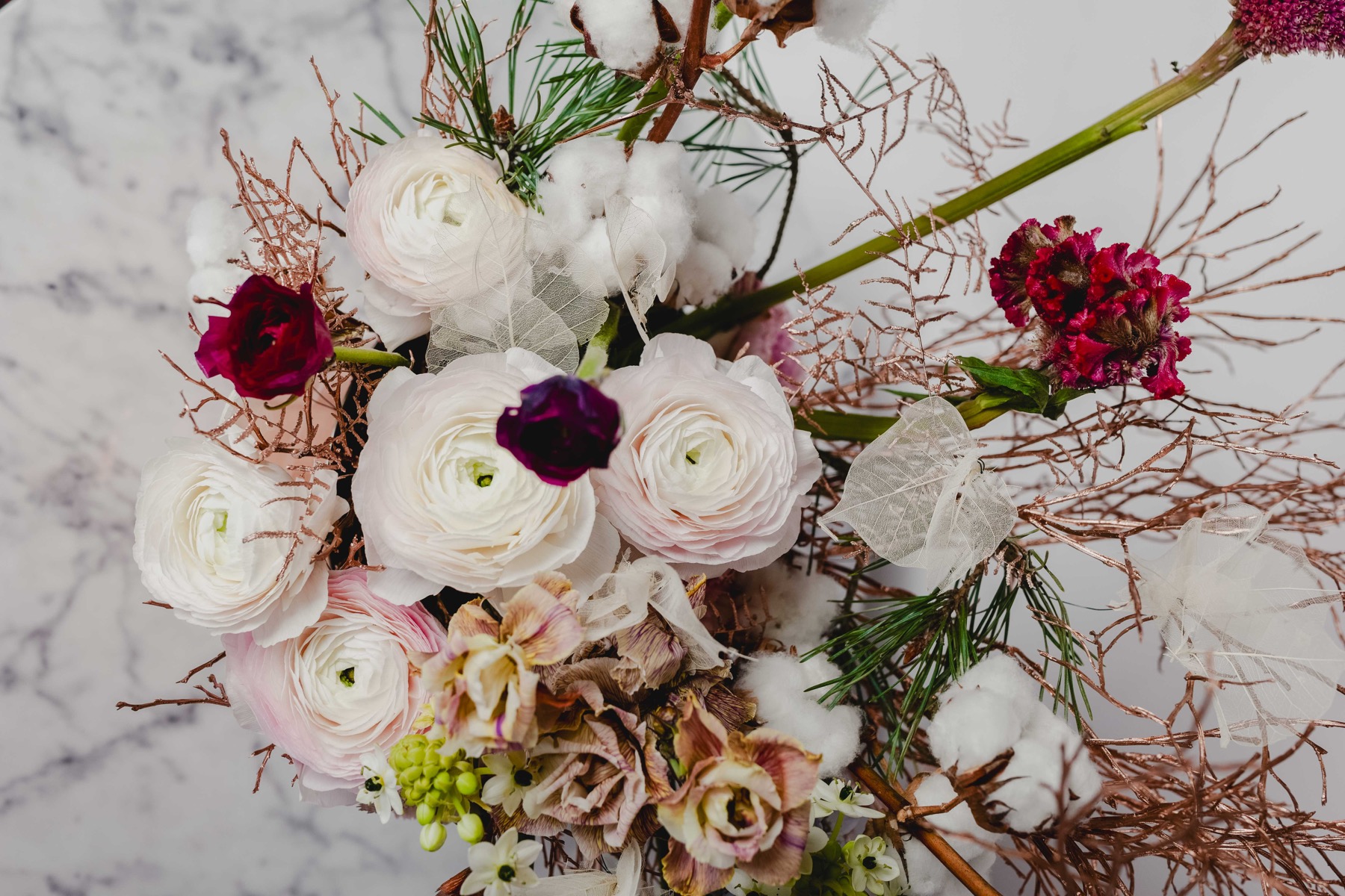 Zarte Ranunkeln, dunkle Rosen und feine Zweige aus Annas floraler Arbeit